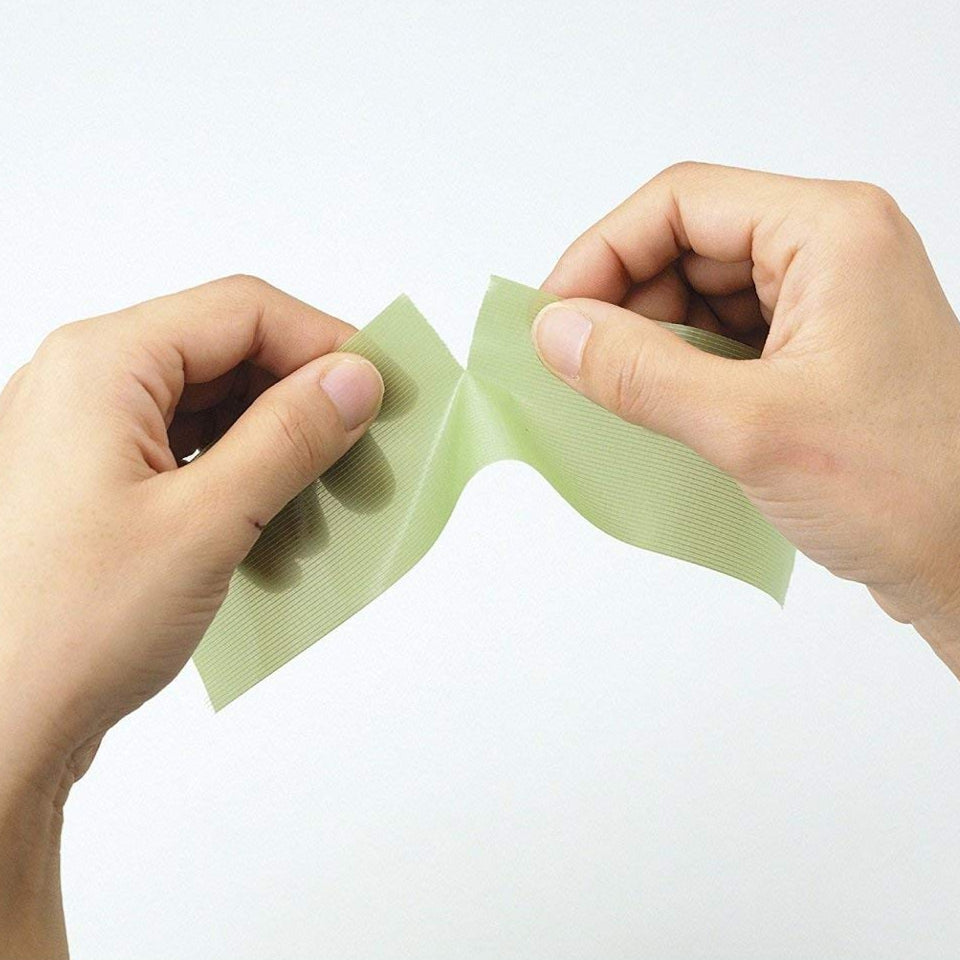 Hands tearing apart a green paper product with Japanese text on a white background