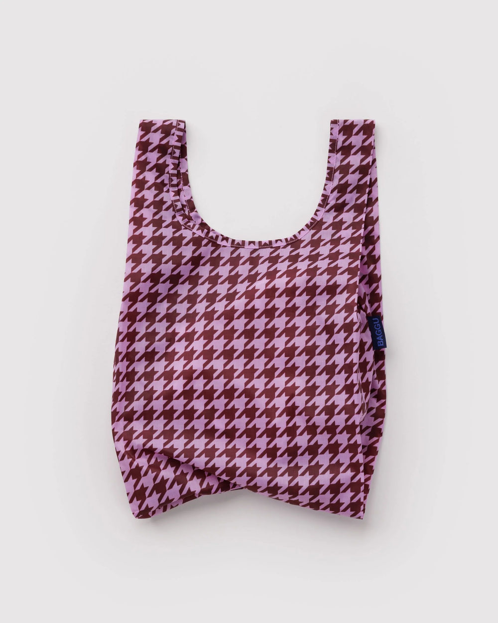 A reusable fabric tote bag with a pink and dark red houndstooth pattern, photographed flat against a light gray background.