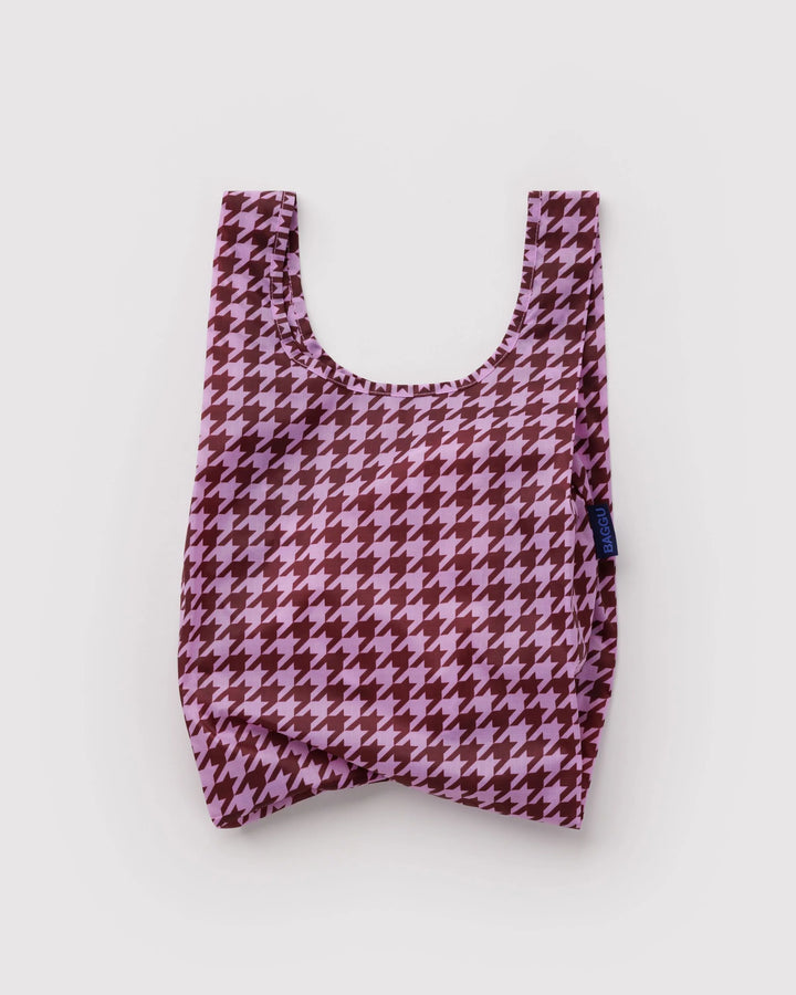 A reusable fabric tote bag with a pink and dark red houndstooth pattern, photographed flat against a light gray background.