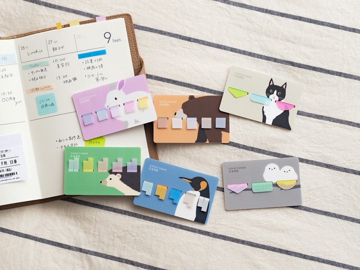 Notebook with colorful sticky notes featuring animal illustrations on a striped background