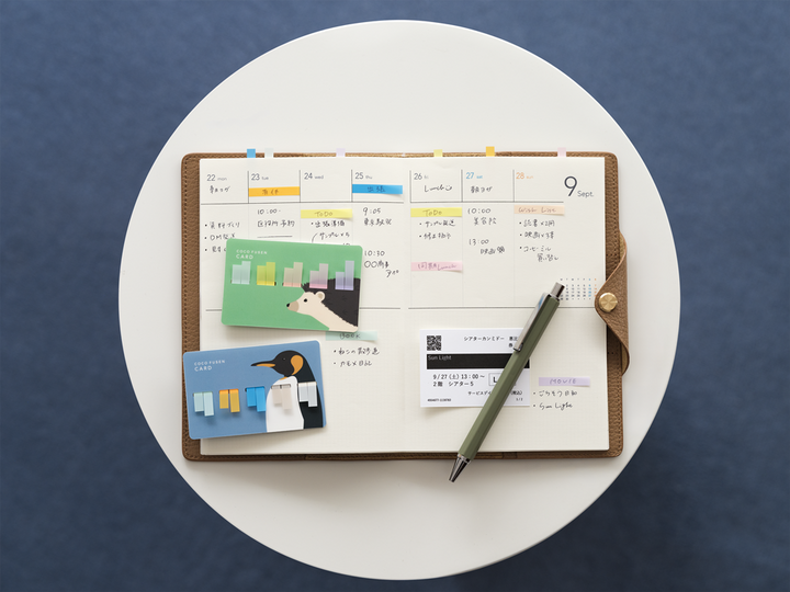 Open planner with stickers and a pen on a white surface