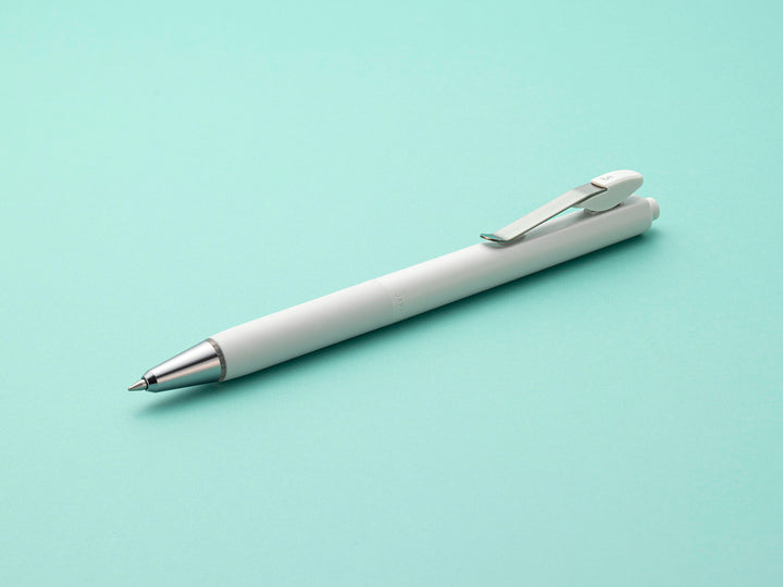 A white Zebra Blen U pen with a metal clip and tip, lying diagonally on a mint green background. The pen is retracted, showing its minimalist, seamless design.